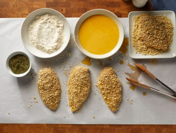 Breaded chicken station set up on a butcher block counter covered in Reynolds Kitchens Countertop Prep Paper