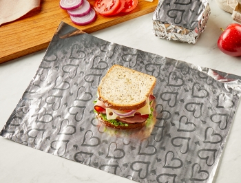 turkey sandwich sitting on a sheet of Reynolds Wrap Fun Foil with embossed heart pattern sitting alongside a lunchbox