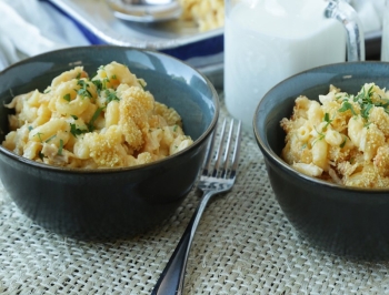 macaroni and cheese casserole sitting in a black bowl on a wood table