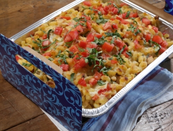 disposable pan with sitting in a carrier filled with tomato basil macaroni and cheese 