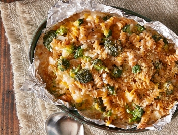 Mac and cheese casserole with broccoli sitting in a casserole dish lined with aluminum foil