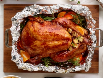 Citrus and herb roasted turkey in an aluminum foil lined baking pan