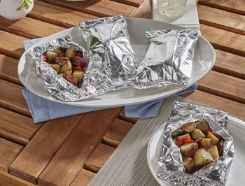 Grilled Potatoes, Onions and Pepper Foil Packet sitting on an outdoor table