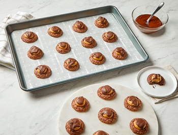 peanut butter chocolate brownie cookies sitting on a baking sheet lined with Reynolds Kitchens Stay Flat Parchment Paper